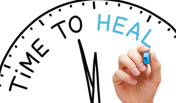 Hand writing Time to Heal concept with blue marker on transparent wipe board.